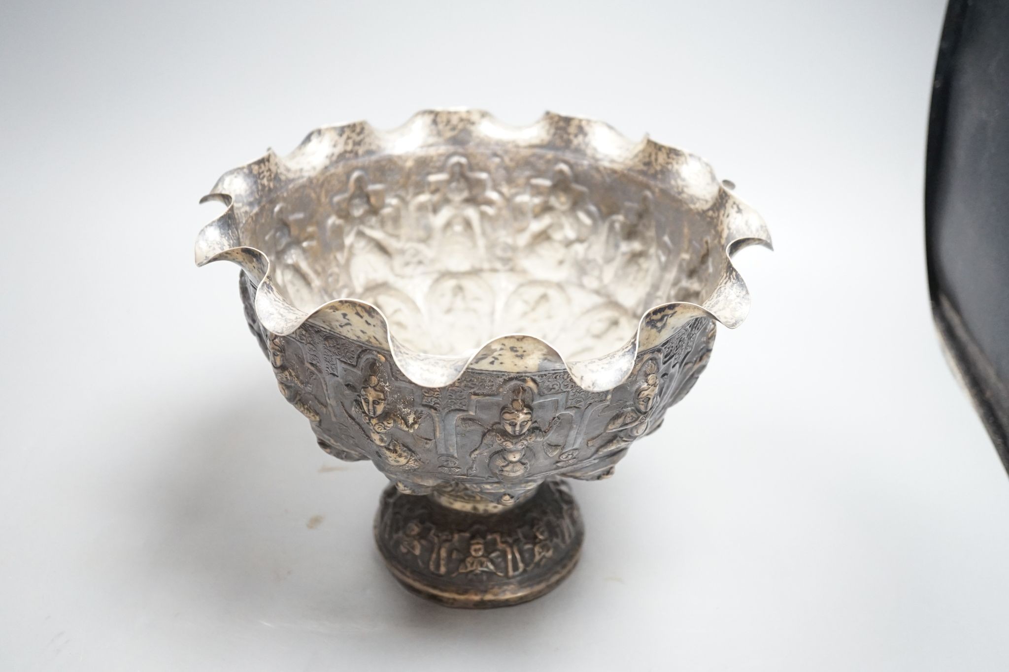 A late 19th century Burmese embossed white metal pedestal bowl, with wavy border, diameter, 27.2cm, 20.5oz.